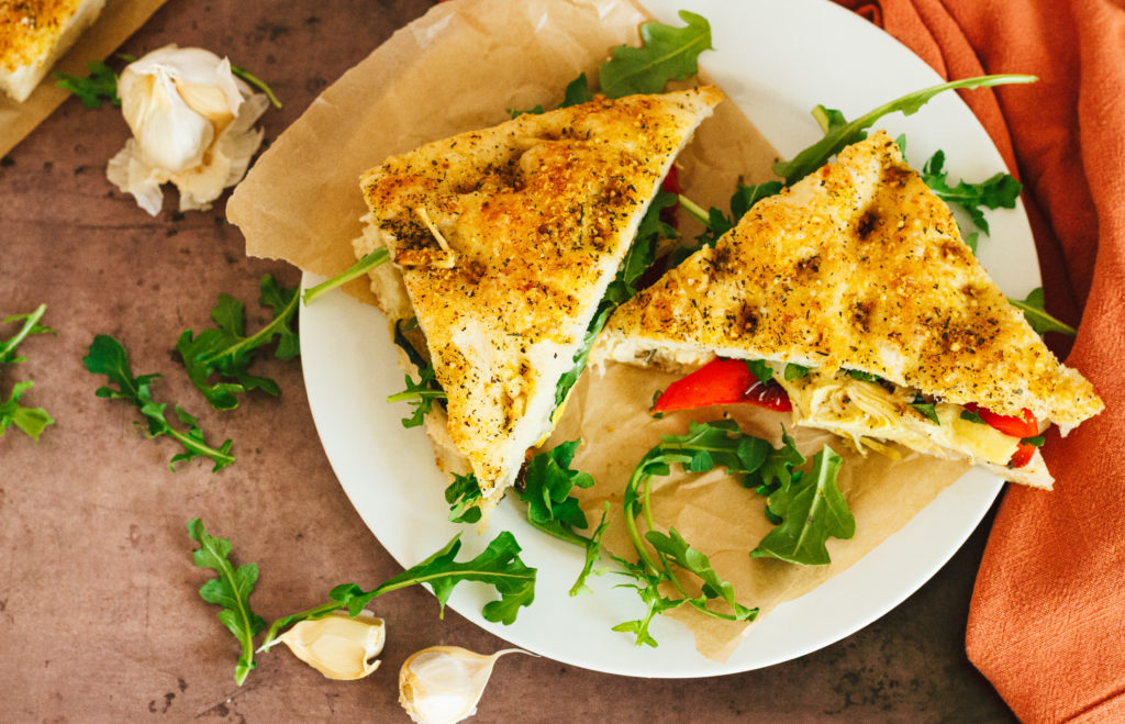 mediterranean veggie focaccia sandwich with garlic rosemary white bean spread